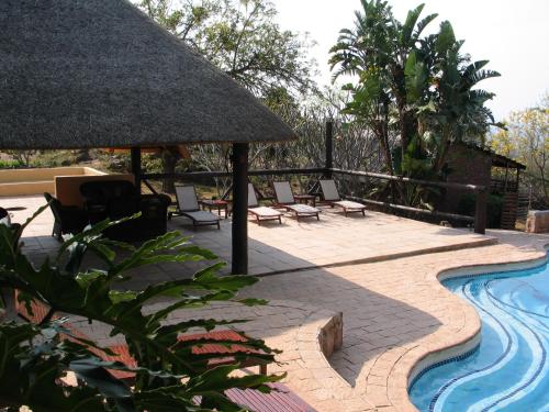 a swimming pool with chairs and a straw umbrella at White House Lodge in White River