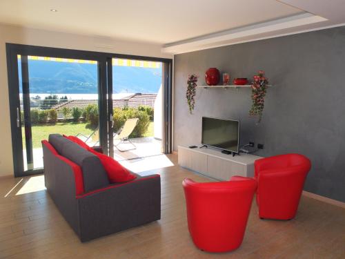 a living room with two red chairs and a television at BELLA VITA Residence in Gravedona