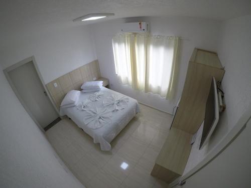 a small bedroom with a bed and a window at Hotel Dove in Foz do Iguaçu
