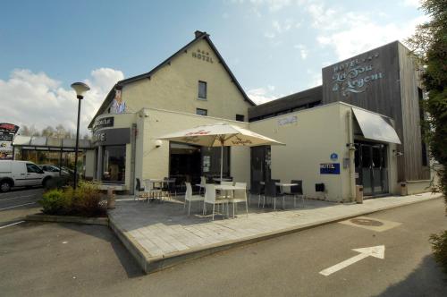 een gebouw met een patio met tafels en een parasol bij Hôtel Le Saint Loup in Gembloux