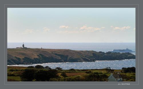 a large body of water with a lighthouse on a hill at Hôtel de la Baie des Trépassés in Plogoff