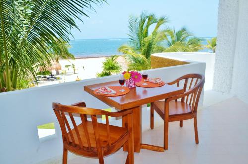 een tafel en stoelen op een balkon met uitzicht op het strand bij Arrecifes Suites in Puerto Morelos