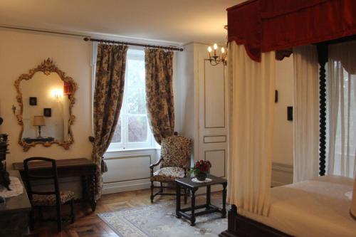 a bedroom with a bed and a chair and a window at Chateau de la Chapelle des Bois in Fleurie