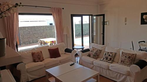 sala de estar con muebles blancos y ventana grande en VILLA BERMEJA 10 by Villitas, en Playa Blanca
