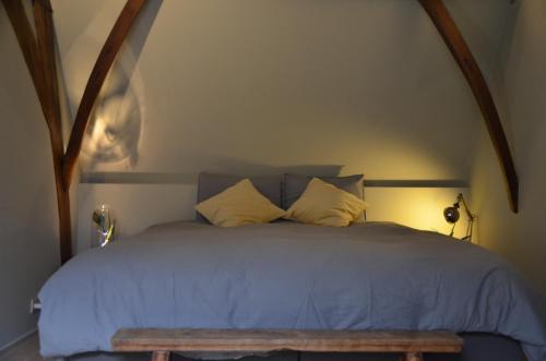 a bed with a blue comforter and two pillows at B&B De Vrome Vos in Mechelen