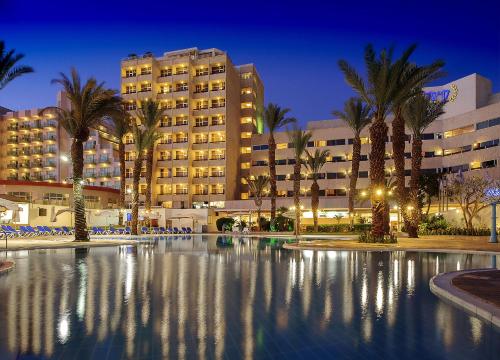 a hotel with palm trees in front of a building at Caesar Premier Eilat Hotel in Eilat