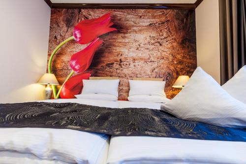 a bedroom with a bed with red flowers on the wall at Akzent Hotel Tietmeyer & Cross Side in Schöppingen