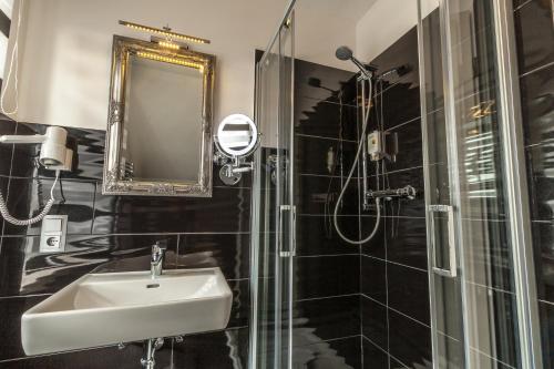a bathroom with a sink and a shower with a mirror at Akzent Hotel Tietmeyer & Cross Side in Schöppingen
