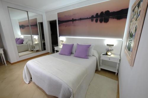 a bedroom with a white bed with purple pillows at Hotel Vila da Guarda in A Guarda