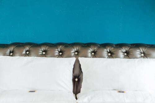 a bed with white pillows and a blue wall at Akzent Hotel Tietmeyer & Cross Side in Schöppingen