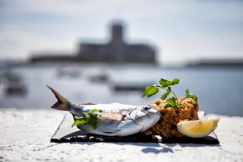 a fish on a plate with a lemon on it at Appartamenti Corollai in Trapani