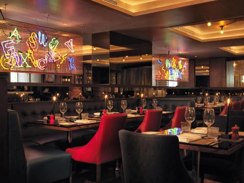 a restaurant with tables and red chairs and lights at Malmaison Birmingham in Birmingham