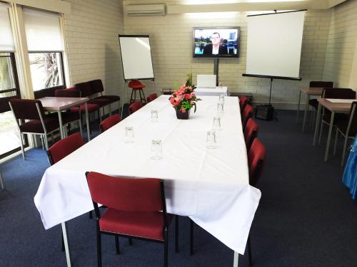 a conference room with a long table and red chairs at Edinburgh Motor Inn in Warragul
