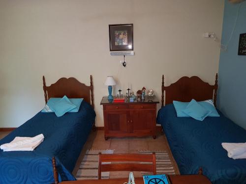 two beds in a room with blue sheets and a table at Loft en Casona Colonial in Santa Rosa