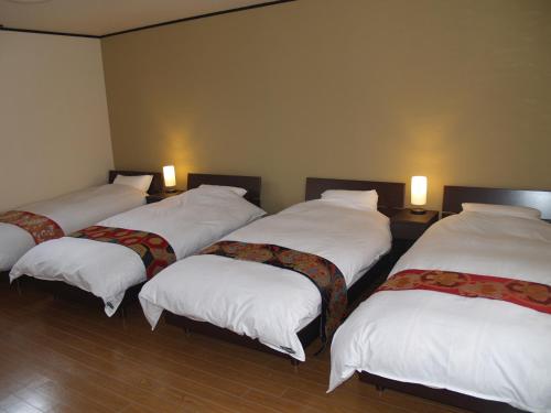 een groep van vier bedden in een kamer met verlichting bij Kyomaru in Kyoto