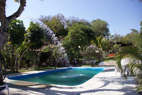 a swimming pool in a park with a fountain at Hotel La Montoya in Curití