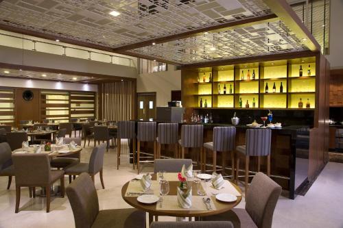 a restaurant with tables and chairs and a bar at Oakwood Residence Whitefield Bangalore in Bengaluru