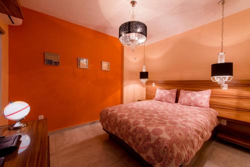 a bedroom with orange walls and a bed and a desk at Once21 Apartment in Guadalajara