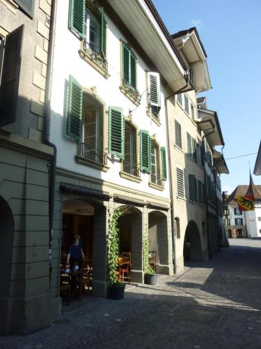 a person sitting at a table in a building with green shutters at Hotel Restaurant Schwert Thun in Thun