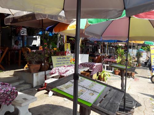 a bench under an umbrella in a market at Vitoonguesthouse2fanrooms & Aircondition in Sukhothai