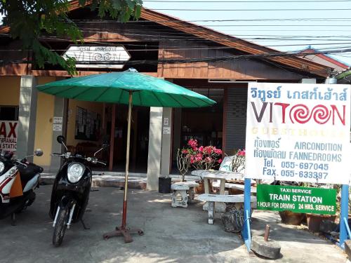 a green umbrella and a motorcycle in front of a building at Vitoonguesthouse2fanrooms & Aircondition in Sukhothai