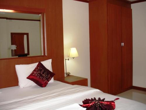 a bedroom with a bed with a red pillow and a mirror at Chinathip Yusabuy in Nan