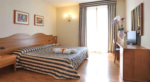 サン・ゼーノ・ディ・モンターニャにあるHotel Costabellaのベッドとテレビが備わるホテルルームです。