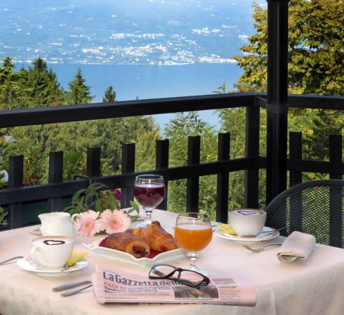 a table with wine glasses and food on a balcony at Hotel Costabella in San Zeno di Montagna