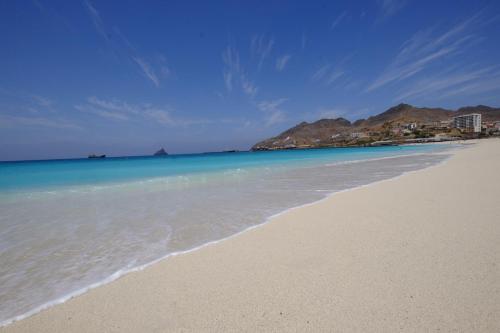 a beach with the ocean and mountains in the background at Casa Comba in Mindelo