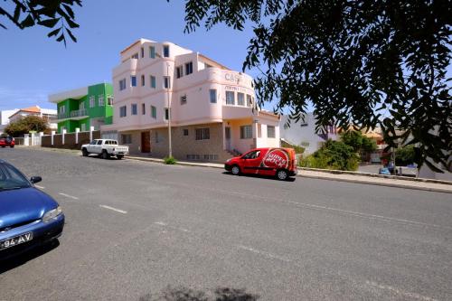 a red car parked in front of a building on a street at Casa Comba in Mindelo