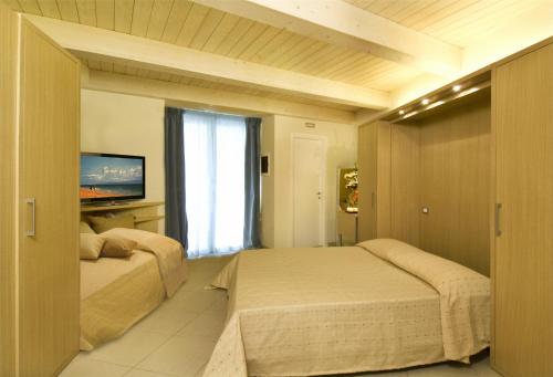 a bedroom with two beds and a tv and a window at Residence Continental Resort in Gabicce Mare