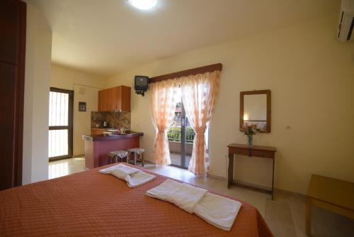a bedroom with a bed with a mirror and a kitchen at Toula's Apartments in Sidari