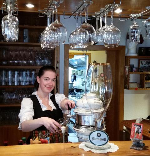 a woman standing behind a counter with a wine glass at Gasthof zum Döhlerwald in Klingenthal