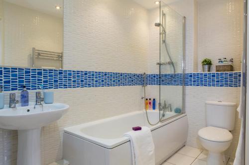 a bathroom with a sink and a tub and a toilet at Borehamwood - Spacious Apartment in Borehamwood