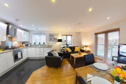 a kitchen and living room with a couch and a table at Borehamwood - Spacious Apartment in Borehamwood