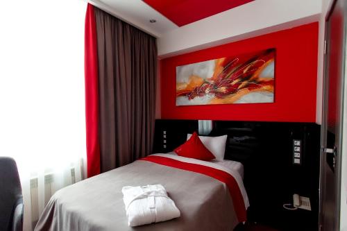 a bedroom with a bed with a red wall at Mildom Premium Hotel in Almaty