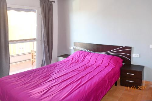 a bedroom with a pink bed with a window at Apartamento Huelin in Málaga
