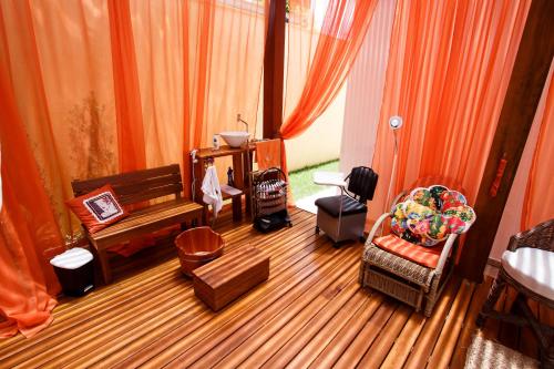 a living room with wooden floors and orange curtains at Pousada Pé na Areia Guarujá in Guarujá