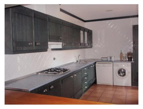 a kitchen with brown cabinets and a stove top oven at Aldeamento Turistico Casas da Comporta in Comporta