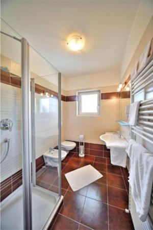 bagno con 2 servizi igienici e doccia in vetro di Pension Steingarten ad Appiano sulla Strada del Vino