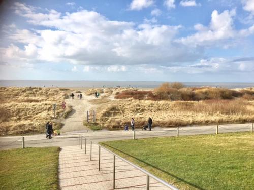 a group of people walking down a path near the beach at Strandstern Norddeich in Norddeich