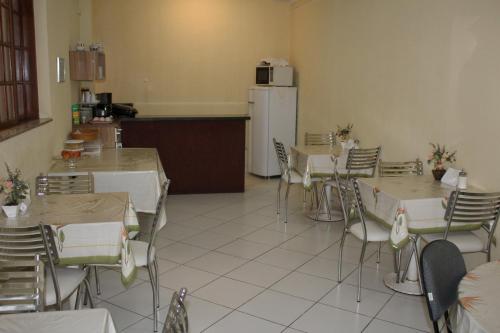 a dining room with tables and chairs and a refrigerator at Hotel Reimann in Indaiatuba