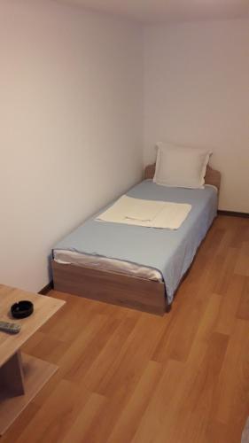 uma pequena cama num quarto com piso em madeira em Magnolia Guest house em Haskovo