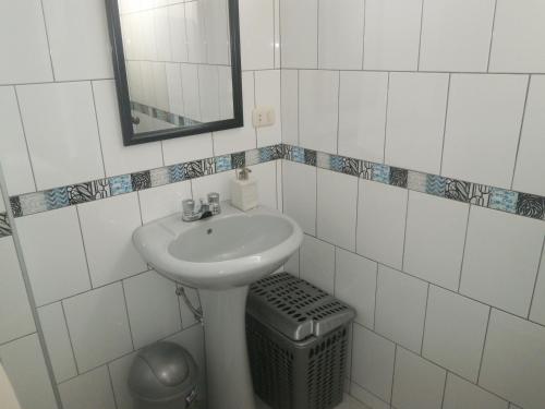 a bathroom with a sink and a mirror and a trash can at Strenua - Las Quintanas in Trujillo