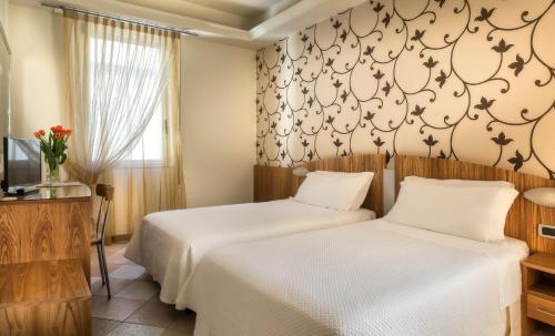 ein Schlafzimmer mit zwei Betten und einem Fernseher in der Unterkunft ACasaMia WelcHome Rimini Hotel By OasiGroup Hotels in Rimini