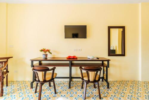 a desk with two chairs and a television on a wall at Le Hua Hotel in Phuket