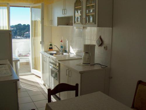 Guest House Mireja في راب: مطبخ بدولاب بيضاء ومغسلة ونافذة
