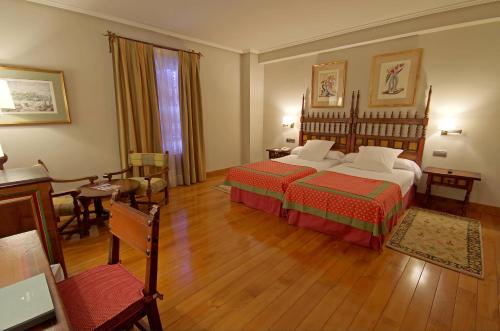 a hotel room with two beds and a table and chairs at Parador de Calahorra in Calahorra