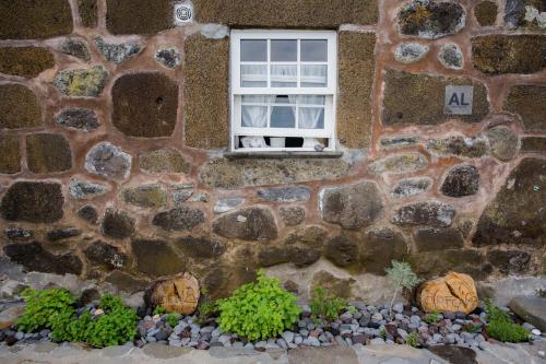 a window in a stone building with a bunch of plants at Caldeira Guesthouse in Fajã da Caldeira de Santo Cristo