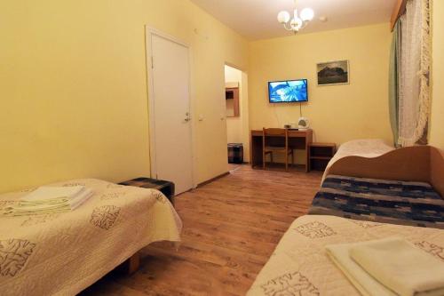 a room with two beds and a desk with a television at Raze in Palanga